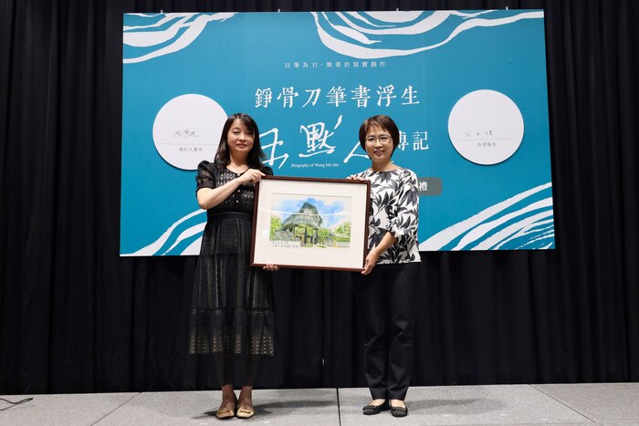 歡迎清華大學加入文學館家族,臺文館館長陳瑩芳(右)致贈建築彩繪紀念品,由王鈺婷代表接受。圖片