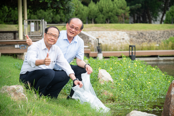 捐助成功湖整治工程的校友代表蔡進步（右）、陳文村施放魚苗到成功湖中。