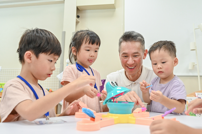 校長高為元（右二）陪小朋友玩餵青蛙的遊戲。