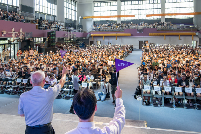 清華大學今天舉辦新生領航營，師長代表揚著清華小旗，新生們也亮起手機手電筒回應。