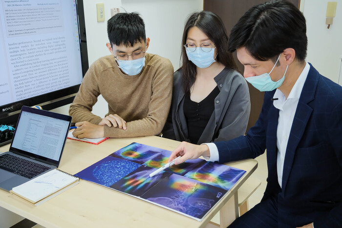 郭柏志（右）與學生討論AI如何從手掌X光影像判斷出人種。